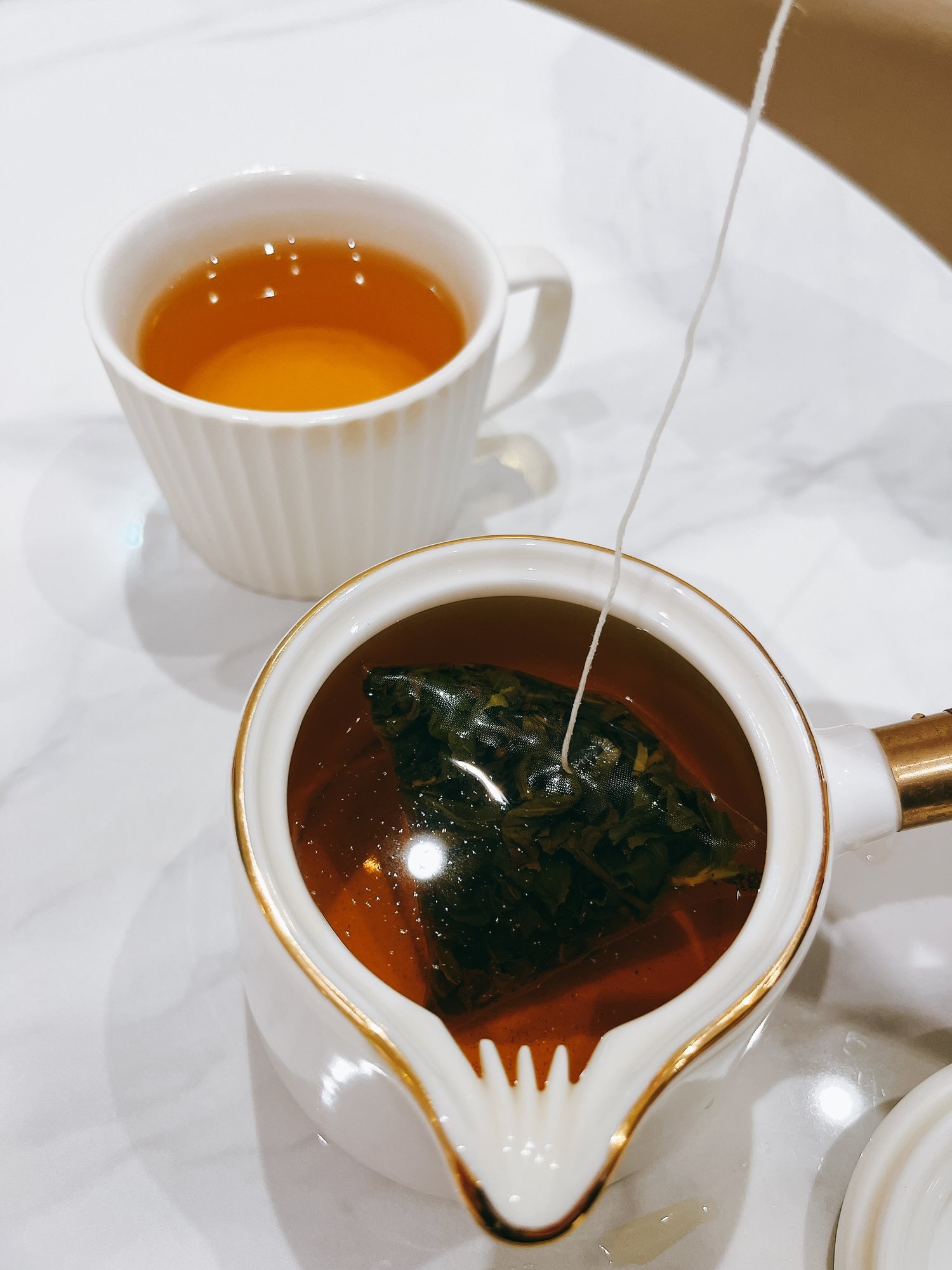 時飴白色金邊茶壺中的熱荔枝烏龍