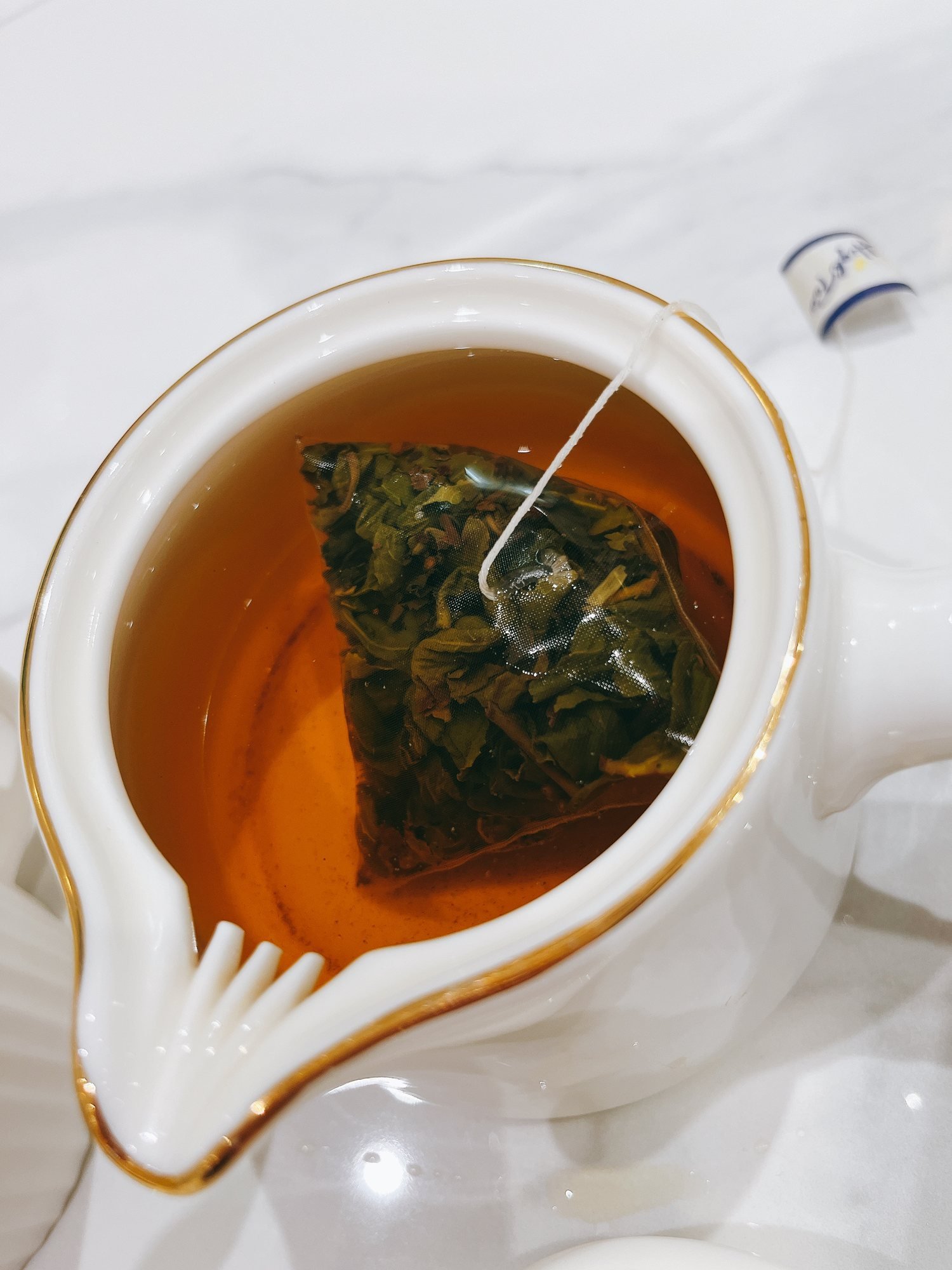 熱荔枝烏龍茶包浸泡在白色茶壺中